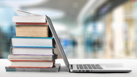 A laptop leans on a pile of books